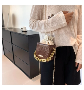 Detail shot of the box bucket bag with dark brown wood grain and gold chain strap