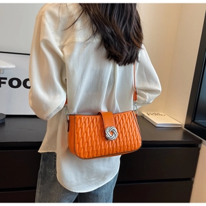 Detail of orange quilted shoulder bag with silver ring buckle and wave pattern texture
