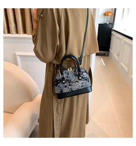 Detail of a floral shell bag with black leather trim worn over the shoulder by a model