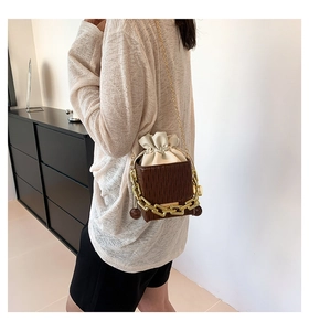 Detail of a brown pleated leather bucket bag with gold chain and white drawstring