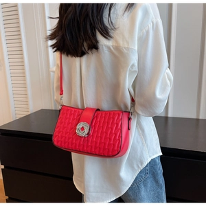 Detail of red quilted crossbody bag featuring silver ring lock and textured surface