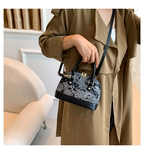 Detail of a chic shell-shaped crossbody bag with traditional wave pattern and gold hardware