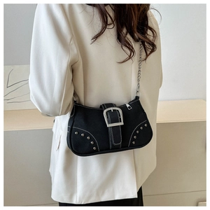 Detail of black canvas shoulder bag featuring silver rivets and metallic chain strap