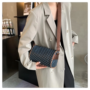 Detail of vintage cylindrical crossbody bag with geometric patterns and brown leather trim