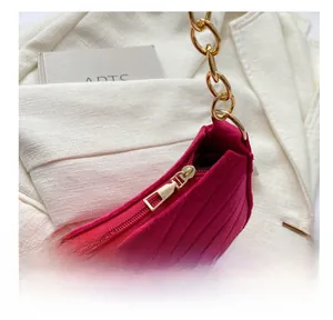 Detailed close-up of smooth zipper and gold chain on fuchsia quilted felt bag