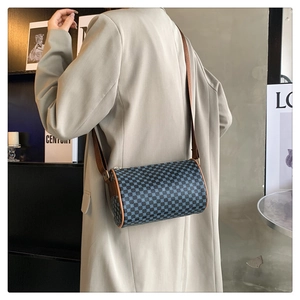 Detail view of retro checkerboard cylinder bag with brown leather strap on model