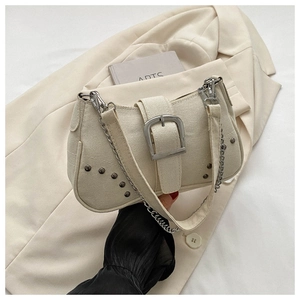 Detailed shot of cream canvas shoulder bag with oversized silver buckle and metal rivets