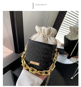 Detail of black wave textured bucket bag with white drawstring pouch and gold chain handle
