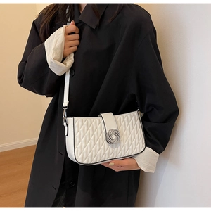 Close-up of a white quilted crossbody bag featuring a decorative silver metal knot buckle