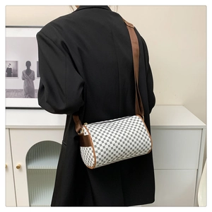 Close-up of a vintage cylinder bag with geometric print and brown leather trim detailing