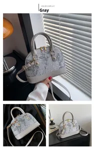 Detail of grey shell-shaped crossbody bag with floral jacquard and leather texture