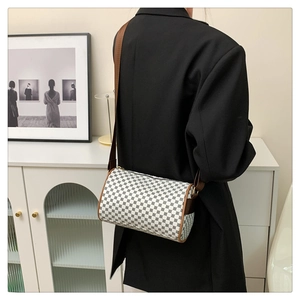 Detailed view of vintage cylinder crossbody bag with retro print on black blazer