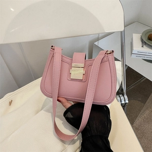 Sac sous le bras en cuir rose avec boucle dorée présenté dans un décor intérieur
