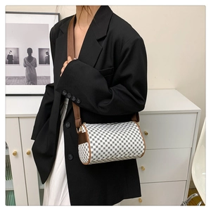 Detail view of a vintage cylinder bag with geometric patterns and brown leather strap