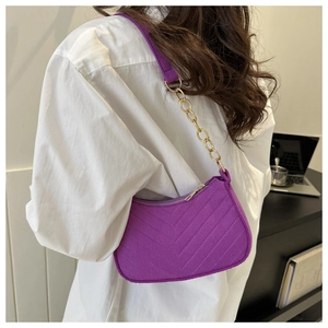 Detail of purple felt baguette bag with V-quilt texture and gold chain strap on model