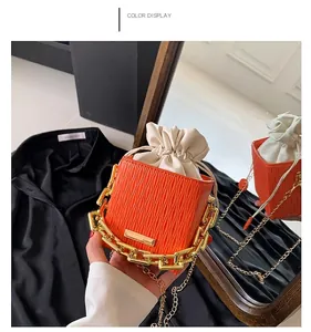 Detail of orange epi-textured bucket bag with golden chain and drawstring closure