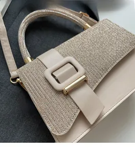 Close-up of beige handbag featuring shimmer fabric textures and wide decorative buckle