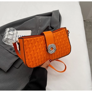 Detail of bright orange quilted crossbody bag with stylish silver metal twist buckle