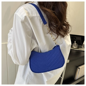 Detail of blue underarm bag featuring V-shaped quilting and gold metal chain strap