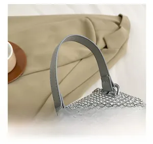 Detail view of the silver studded handbag featuring a grey leather handle and metal D-rings
