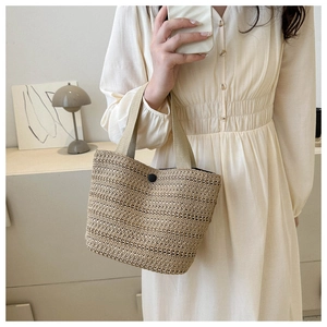 Détail du sac cabas chic en paille tressée avec bouton noir et anses marron clair