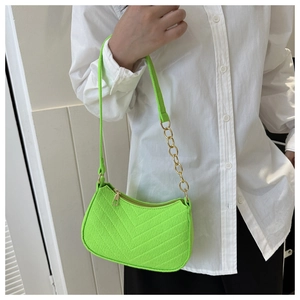 Détail du sac sous l'aisselle vert néon avec texture matelassée en V et chaîne dorée