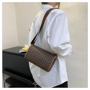 Model wearing a vintage cylinder crossbody bag with brown geometric print and gold hardware