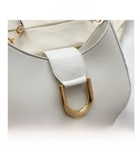 Vue macro d'une boucle dorée en U sur un sac de selle semi-circulaire blanc élégant
