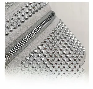 Macro detail of grey suede handbag featuring silver rivet studs and metallic zipper