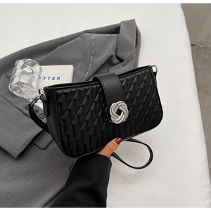 Detail showing black quilted faux leather bag with silver knot buckle and wavy stitch texture