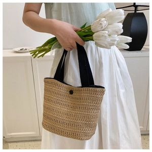 Gros plan détaillé d'un sac cabas tissé beige avec sangle noire et bouton de fermeture