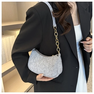 Detail of grey felt shoulder bag featuring textured fabric and gold metal chain strap