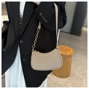 Détail d'un sac à bandoulière matelassé kaki clair avec chaîne dorée sur un mannequin