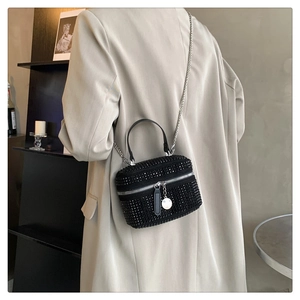 Close-up of black rhinestone mini box bag with silver chain strap worn by a model