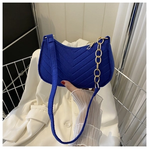 Detail of dark blue velvet crescent bag with V-shaped quilting and gold chain strap