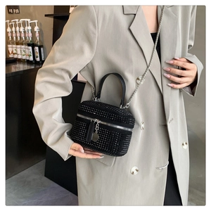 Close-up of black rhinestone handbag with silver chain strap shown on model attire