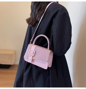 Model wearing a pink handbag with glitter flap and buckle on a black coat