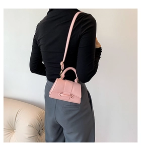 Detailed macro view of pink litchi grain texture on the small crossbody bag strap and handle