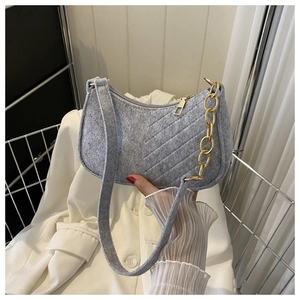 Detail of grey felt shoulder bag featuring diagonal quilting and gold metal chain strap