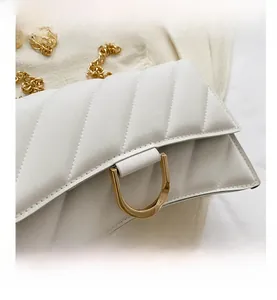 Close-up of white quilted leather texture with gold D-ring hardware and metal chain strap