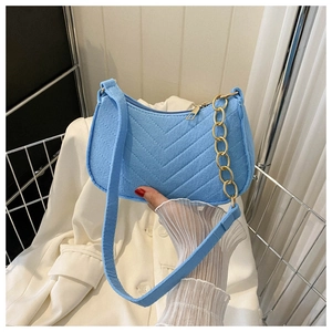 Detail view of light blue felt baguette bag with V-shaped quilting and gold chain strap