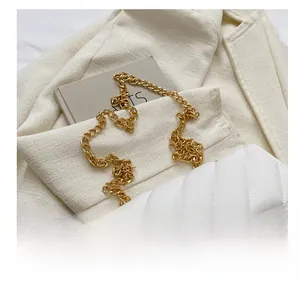 Close-up of white quilted handbag featuring chunky gold chain strap and metal U-clasp
