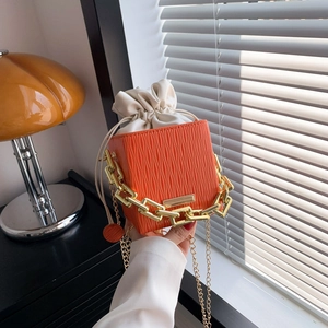 Chic orange textured leather bucket bag with chunky gold chain handle and drawstring pouch