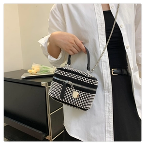 Detail of black mini crossbody bag with silver studs and chain strap on a model
