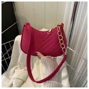 Detail of fuchsia quilted shoulder bag with velvet texture and golden chain strap