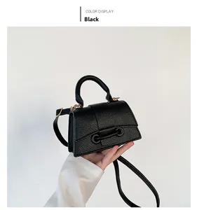 Detail of black crossbody bag with litchi grain leather and golden hardware buckle