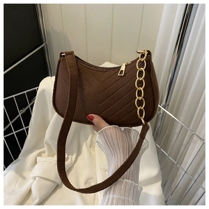 Detail of brown suede crescent bag featuring V-shaped quilting and gold chain strap