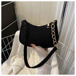 Detail of black crescent shoulder bag featuring V-shaped quilting and gold chain strap