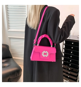 Detail of rose pink handbag with rhinestone buckle and ruffled handle worn cross-body