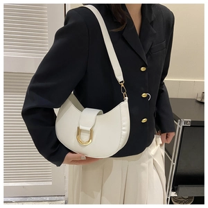 Gros plan d'un sac à bandoulière blanc en demi-lune avec boucle en U dorée sur un mannequin